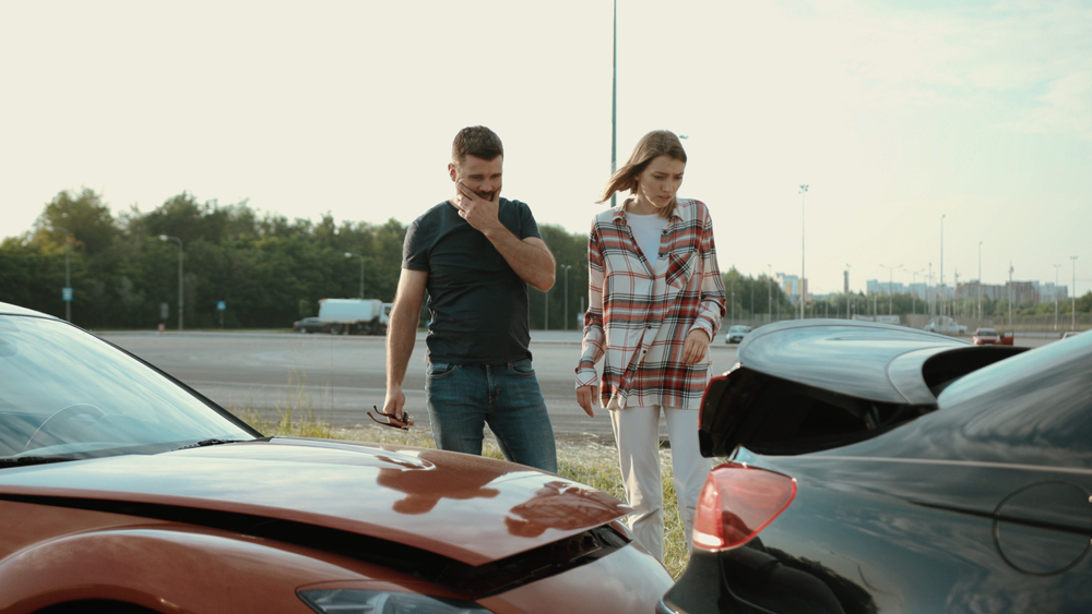 Man and woman looking at their cars that have collided into each other