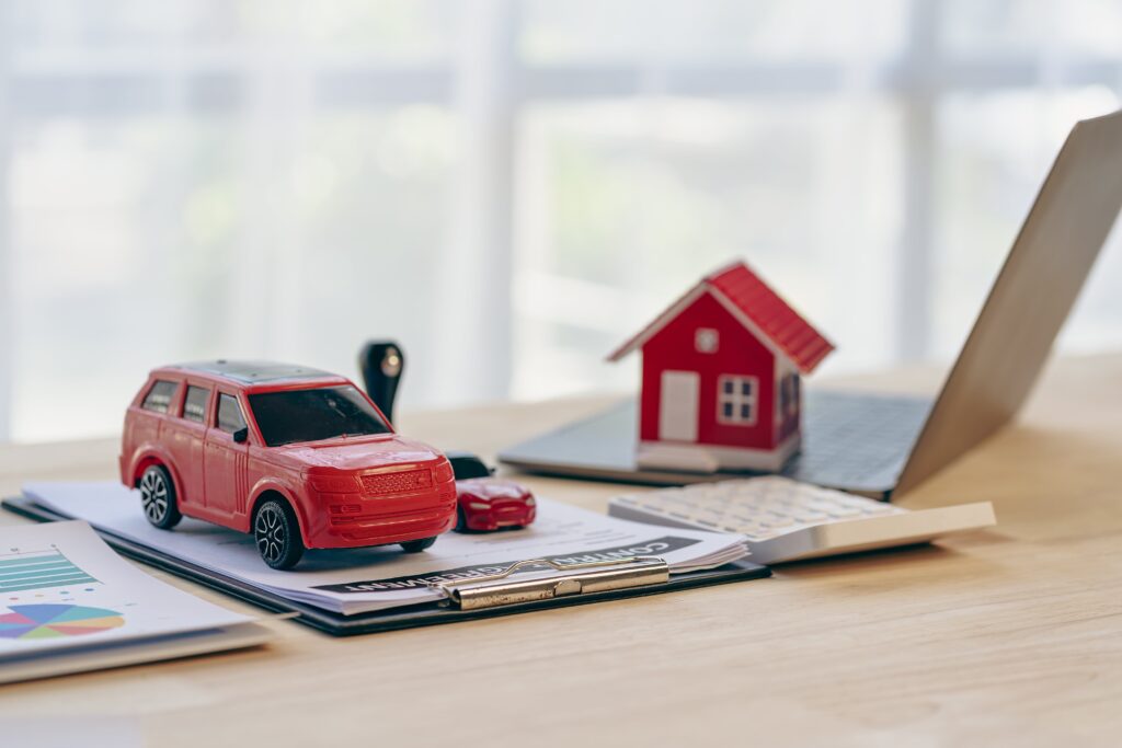 model house and car on desk with open laptop